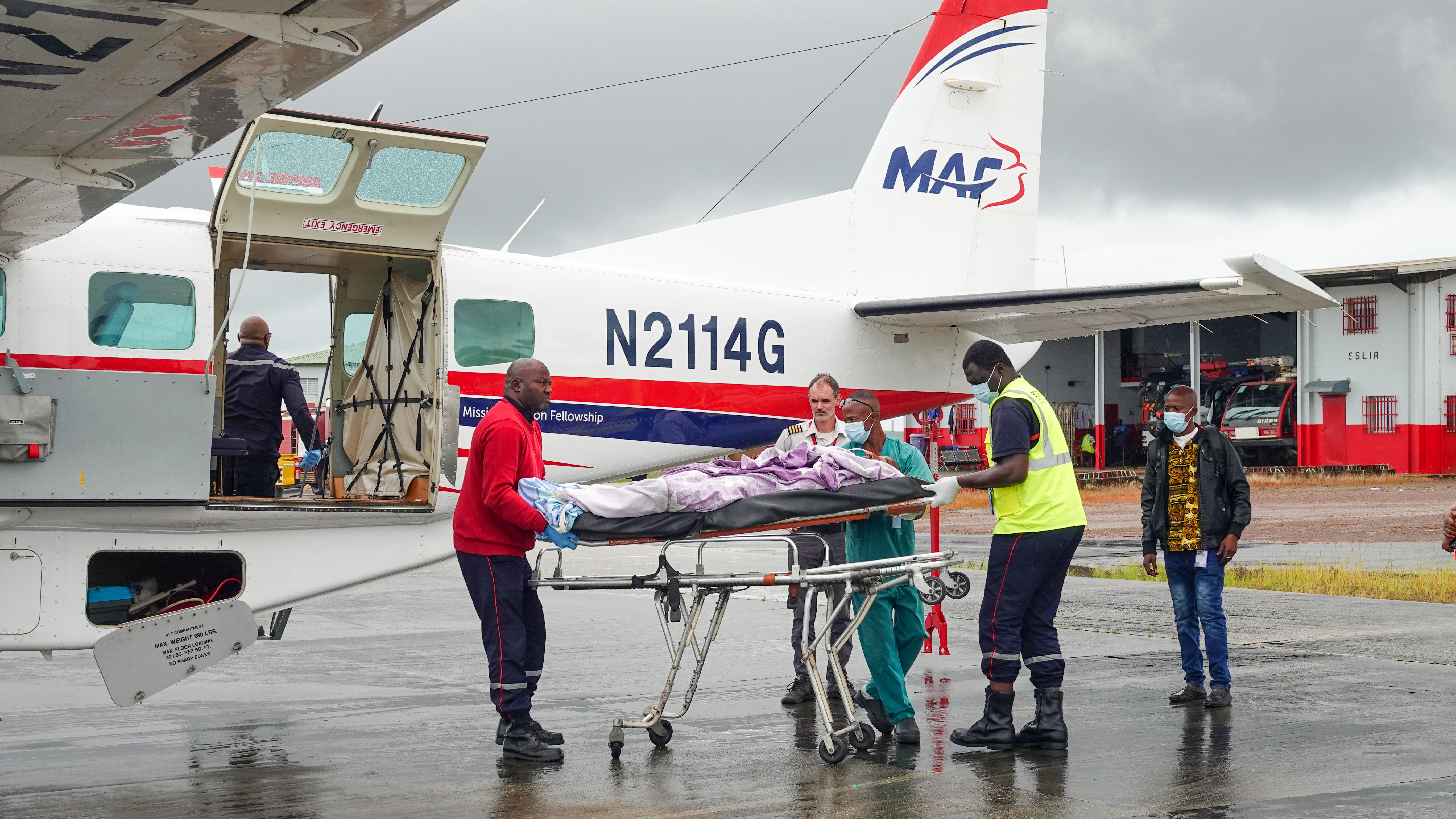 A man on a stretcher being lifted into a MAF aircraft.